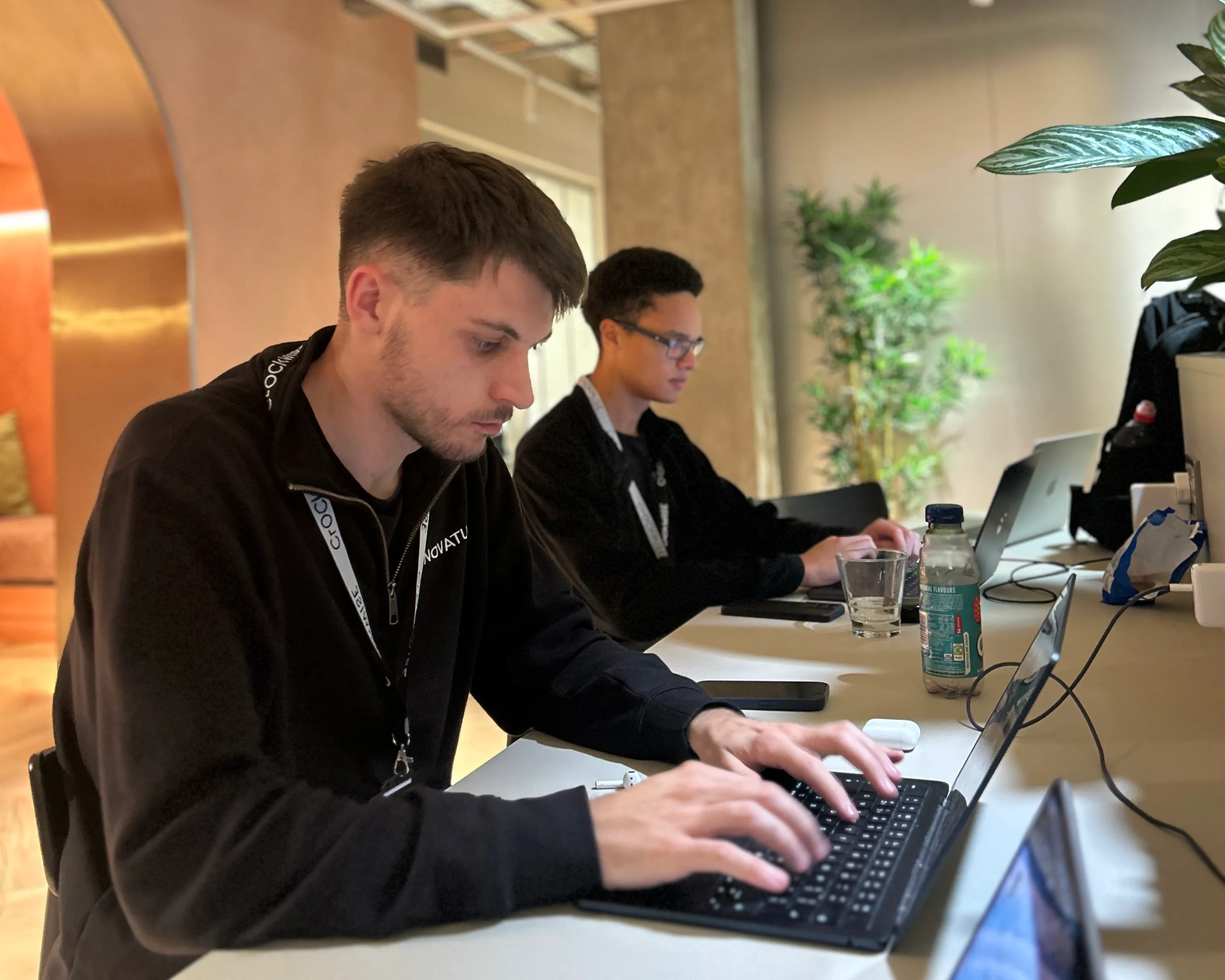 Max and Niall from Novatura writing code on a project side by side